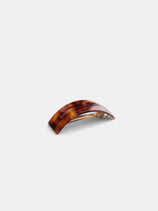 The Rectangle Volume Hairclip is a brown tortoiseshell clip with a curved design and secure steel clasp, handcrafted in France. Shown on a plain white background.