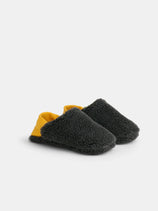 Sherpa House Shoes: Cozy, fuzzy, machine washable slippers featuring dark gray textured fabric and a yellow heel detail, shown on a plain white background.