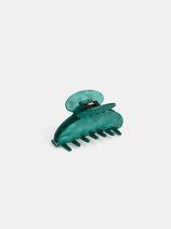 The Large Round Claw, a translucent teal acetate hair clip with a curved design and interlocking teeth, handcrafted in France, is displayed on a plain white background.