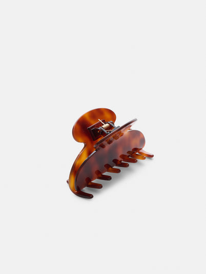 The Large Round Claw, a brown tortoiseshell-patterned acetate hair accessory with wide teeth, is displayed upright on a plain white background.