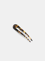 The Oval Hair Pin, featuring a tortoiseshell pattern and two prongs, is handcrafted in France from premium acetate and is shown on a plain white background.