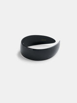 The Wide Headband, handcrafted from premium acetate, features a sleek, glossy black crescent shape and minimalist design with a slightly curved, wide structure. It is displayed on a plain white background.