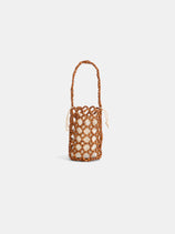 The Riviera Beaded Mini Bag is a small cylindrical purse with a cream cotton-lined pouch, brown netted woven exterior, and matching handle, shown against a plain white background.