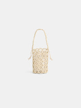 The Riviera Beaded Mini Bag is a small beige cylindrical artisan bag with a netted, knotted rope exterior and braided handle, shown against a plain white background.