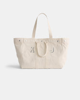 The Perfect Weekend Tote is a spacious off-white cotton bag with two handles and silver rivets. Featuring gray 