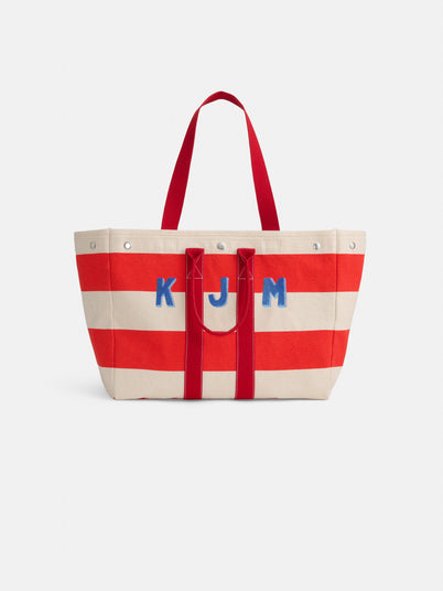 The Perfect Striped Weekend Tote features wide red and off-white stripes, red handles, and blue "KJM" initials on the front.