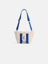 The Mini is a small cream cotton canvas tote with bright blue handles and strap, featuring a red embroidered letter E on the front.