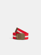 The Striped Web Belt, featuring red fabric with a white center stripe and an antique brass buckle, is coiled neatly against a plain white background.
