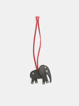 An Elephant Charm in Leather made of grey leather hanging from a long red cord.