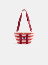 The Painted Striped Mini is a small tote bag with red and white horizontal stripes, red handles, a wide red shoulder strap, and a blue "M" on the front pocket, shown against a plain white background.