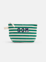 The Painted Perfect Striped Canvas Pouch features green and white horizontal stripes, a white zipper, and navy blue "SOM" lettering on the front.