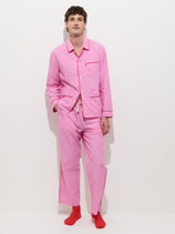 A man wearing a pink and white striped Snooze Striped Pant in Cotton matching set, consisting of a button-down shirt and trousers paired with bright red socks.