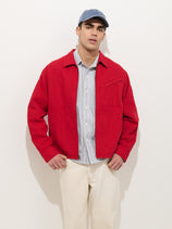 A man wearing the Andre Zip Jacket In Linen Twill over a light blue shirt, cream cotton-linen twill pants, and a blue baseball cap stands against a plain white background.