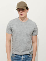 A young man in a brown baseball cap, blue jeans, and the Standard T-Shirt In Slub Cotton stands against a plain white background, looking at the camera with a neutral expression.
