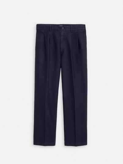 The Double Pleated Pant in Vintage Twill is a pair of dark navy blue men's cotton pants with a straight-leg fit, belt loops, button closure, and side pockets, shown laid flat on a plain white background.