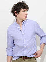 A person with curly brown hair wearing the Mill Striped Shirt in Thomas Mason and khaki pants looks to the side against a plain white background.