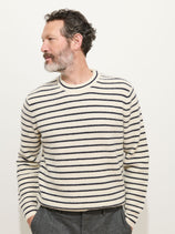 A man with short curly hair and a beard, wearing the Jordan Sweater in striped cashmere, looks to his left while standing against a plain white background.