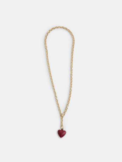 The Roxanne Assoulin Mini Puffy Heart Necklace, featuring a gold brass cable chain and a shiny dark red puffy heart pendant, is displayed on a plain white background.