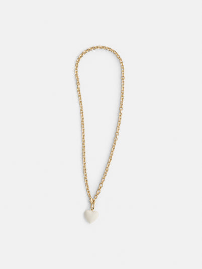 The Roxanne Assoulin Mini Puffy Heart Necklace features a gold brass cable chain with a small white puffy heart pendant, shown on a plain white background.
