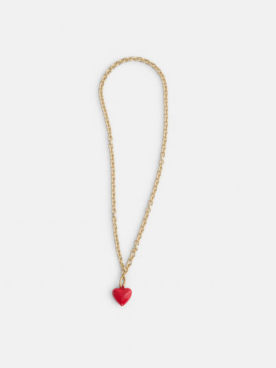 The Roxanne Assoulin Mini Puffy Heart Necklace features a gold heart charm with a red heart-shaped pendant on a brass cable chain, displayed against a white background.