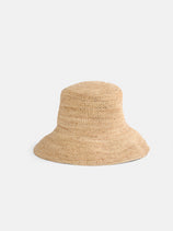 The Straw Bucket Hat, in natural straw color with a wide brim and adjustable sizing, is the perfect summer accessory, shown on a plain white background.