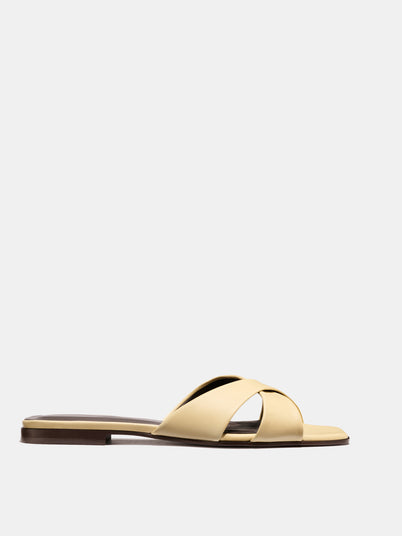 The Alex Mill x Margaux: The Selene Flat Sandal - Butter Nappa is a handmade beige slide with open toe and crisscross Nappa leather straps, crafted in Spain and shown on a plain white background.