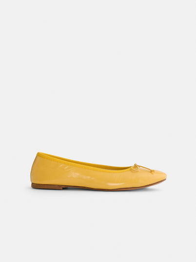 The Prince Street Ballet Flat, a yellow Italian leather shoe with a small bow on the toe, is shown in side profile against a plain white background.