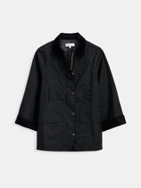 The Chiltern Street Jacket in waxed cotton is black, features a collar, two front pockets, three-quarter sleeves, and is water-repellent. Displayed on a plain white background.