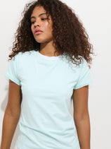 A woman with curly hair wears the Prospect Tee In Cotton Jersey, a white, garment-dyed shirt made in Peru.