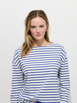 A young woman with long blonde hair, wearing the Avignon Striped Tee In Cotton, stands against a plain white background and looks at the camera with a neutral expression.
