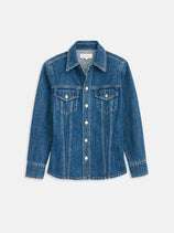 Annabelle Shirt In Denim: blue vintage denim jacket featuring long sleeves, pointed collar, two chest pockets with button flaps, and visible seams. Crafted from 100% cotton crosshatch denim and displayed flat on a white background.