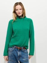 A person wears the Eastport Rollneck In Cotton in bright green with blue jeans and a brown belt, standing against a plain white background and looking directly at the camera with a neutral expression.