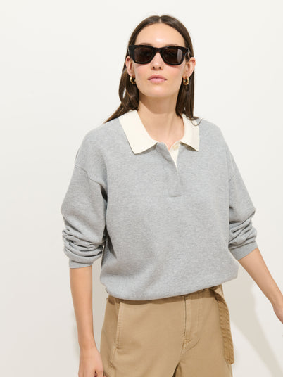 A woman wearing black sunglasses, tan pants, and the Bond St Polo In Cotton Cashmere stands against a plain light background.