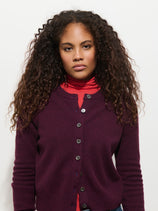 A woman wearing an Elizabeth Street Cardigan in Merino Wool over a red turtleneck.